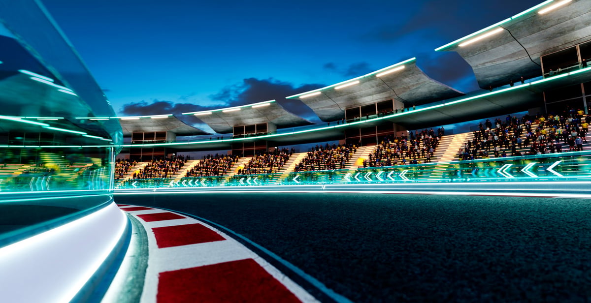 Modern motorsport stadium with glowing track edges and seated spectators under a dark sky